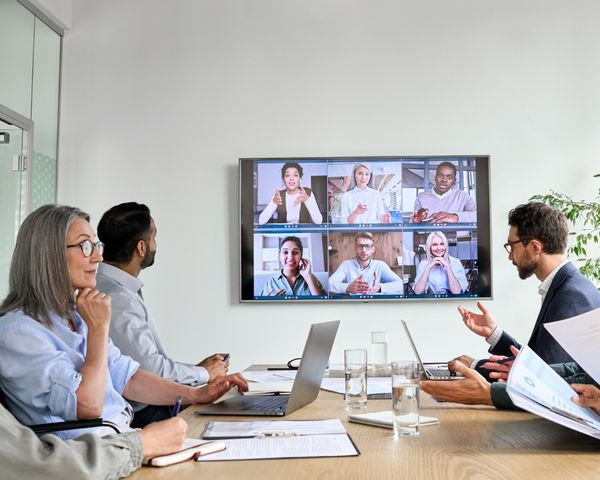 Videokonferenz in einem Konferenzraum mit mehreren Mitarbeitenden in einem größeren Unternehmen