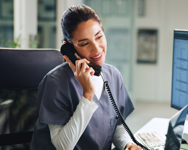Mitarbeiterin telefoniert am Arbeitsplatz mit fester Rufnummer im Unternehmen
