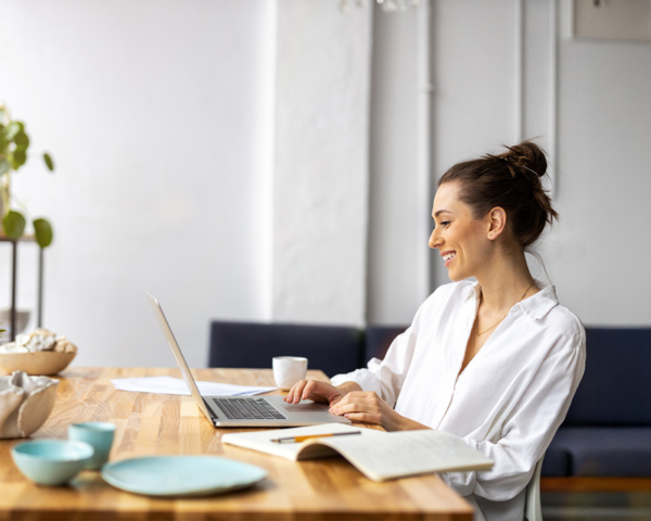 Frau sitzt zurückgelehnt am Schreibtisch mit Laptop