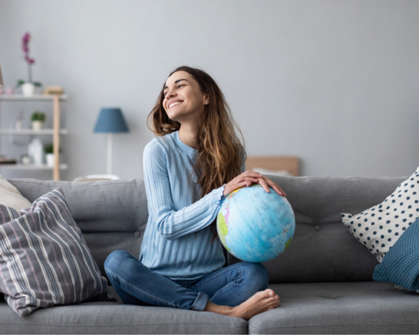 Frau auf dem Sofa hat einen Globus in der Hand