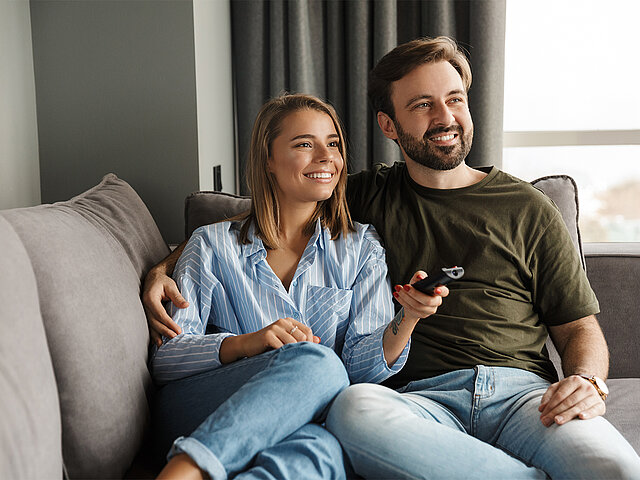 Pärchen liegt auf dem Sofa guckt Fernsehen 