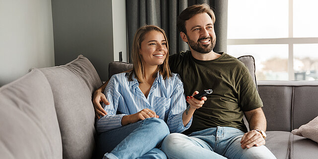 Pärchen liegt auf dem Sofa guckt Fernsehen 