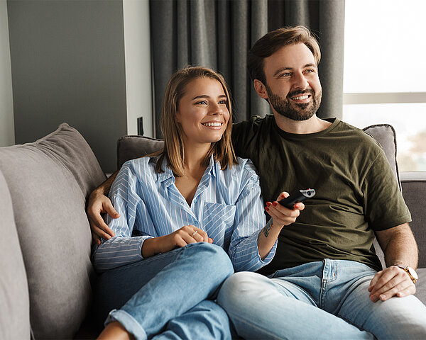 Pärchen liegt auf dem Sofa guckt Fernsehen 