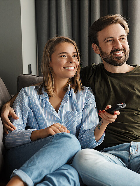 Pärchen liegt auf dem Sofa guckt Fernsehen 