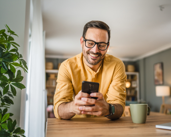 Mann lehnt sich auf einem Tisch mit einem Telefon in der Hand