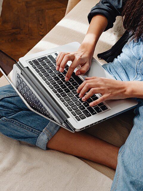 Person sitzt im Schneidersitz auf einem Sofa