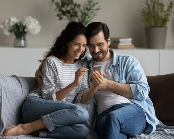 Pärchen auf dem Sofa mit Telefon in der Hand